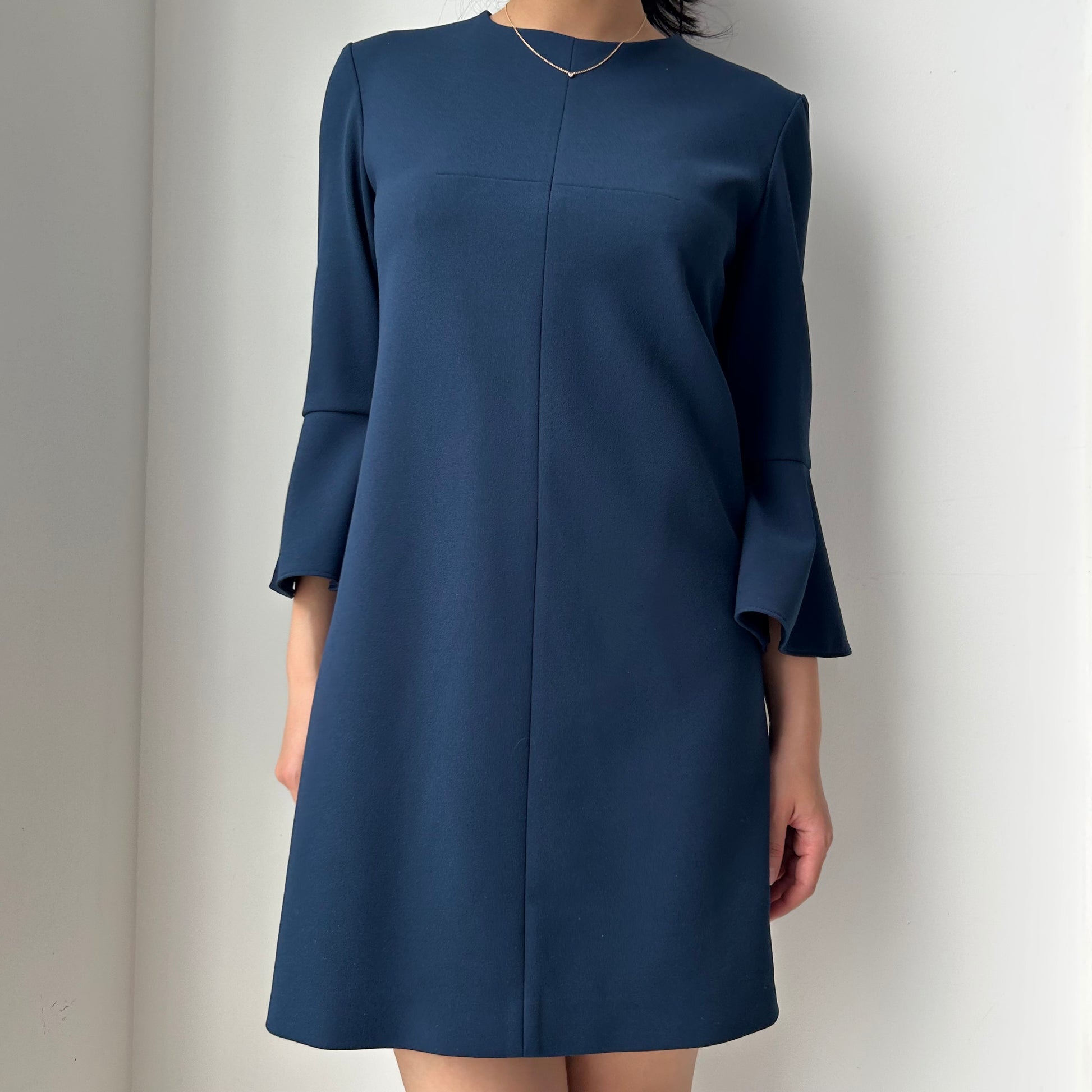 Navy blue dress worn by a person on a plain background