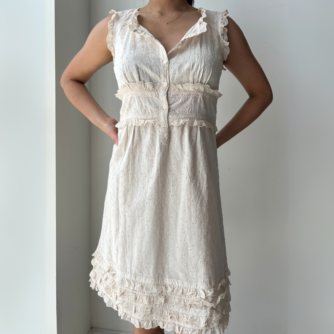 White dress with ruffled details worn by a person against a plain background