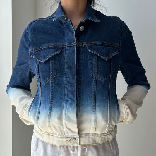 Blue denim jacket with gradient effect worn by a person on a plain background